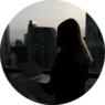 Person arbeitet am Laptop mit Stadtsilhouette im Hintergrund